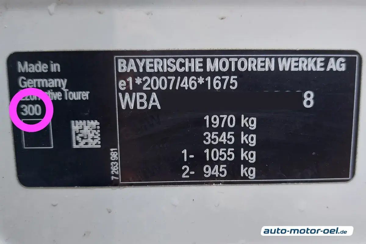 BMW Farbcode vom Typenschild ablesen: Eine Nahaufnahme eines schwarzen Typenschilds (Plakette) an einem weißen Fahrzeuggehäuse. Links auf dem Schild ist die Zahl "300" mit einem pinkfarbenen Kreis markiert. Der Text auf dem Schild umfasst unter anderem „BAYERISCHE MOTOREN WERKE AG“ sowie verschiedene Gewichtsangaben in Kilogramm (kg) und eine ausgegraute Identifikationsnummer (WBA...). Das Licht ist hell und gleichmäßig, die Oberfläche des Fahrzeugs wirkt glatt und sauber.