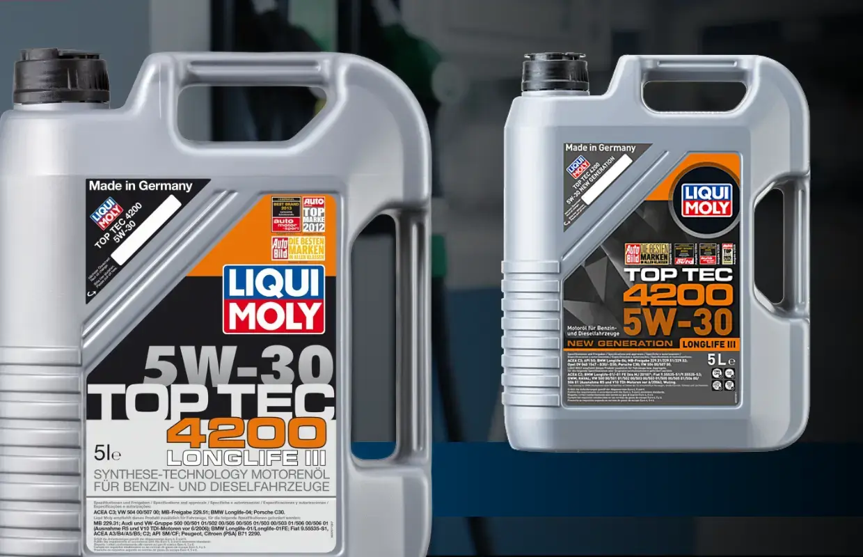 Liqui Moly Top Tec 4200 New Generation Screenshot: Zwei graue 5-Liter-Kunststoffkanister mit Motoröl der Marke Liqui Moly stehen vor einem unscharfen, bläulichen Hintergrund. Der linke Kanister ist groß im Vordergrund platziert, der rechte etwas kleiner und nach hinten versetzt. Die Etiketten sind schwarz, orange und weiß gestaltet und zeigen prominent die Aufschrift „5W-30 TOP TEC 4200 LONGLIFE III New generation“ sowie das Firmenlogo. Auf dem Etikett sind zudem verschiedene Herstellerfreigaben und Qualitätssiegel abgebildet.